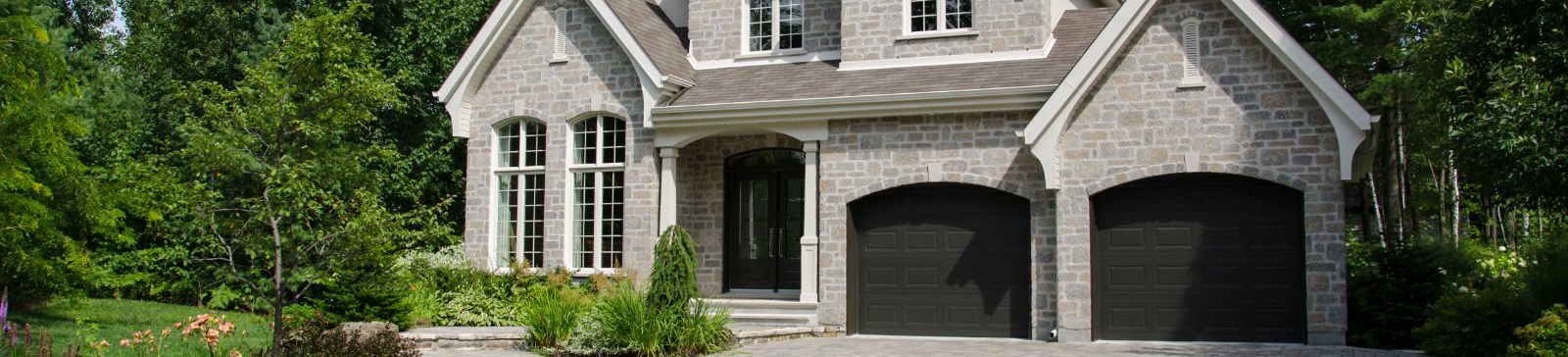 Stylish Stone Home with Double Garage in Alpine, CA Beautiful residential home with a double garage and stone exterior surrounded by greenery, representing reliable garage door repair in Alpine, CA.