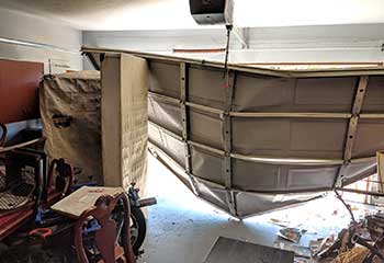 Severely damaged white steel garage door detached from frame after car impact in Spring Valley, CA
