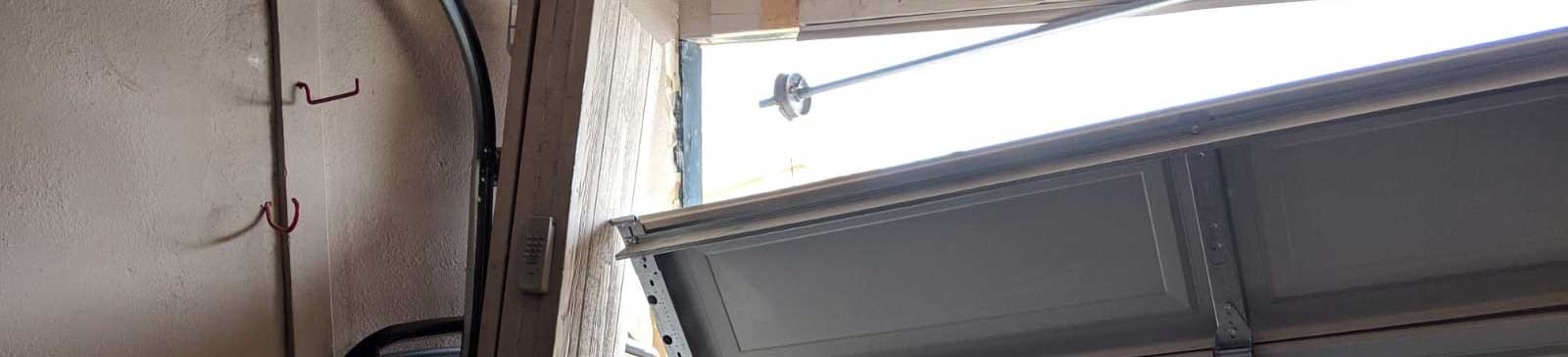 Severely damaged white steel garage door detached from frame after car impact in Spring Valley, CA