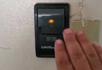 Hand testing LiftMaster remote control after repair in garage setting